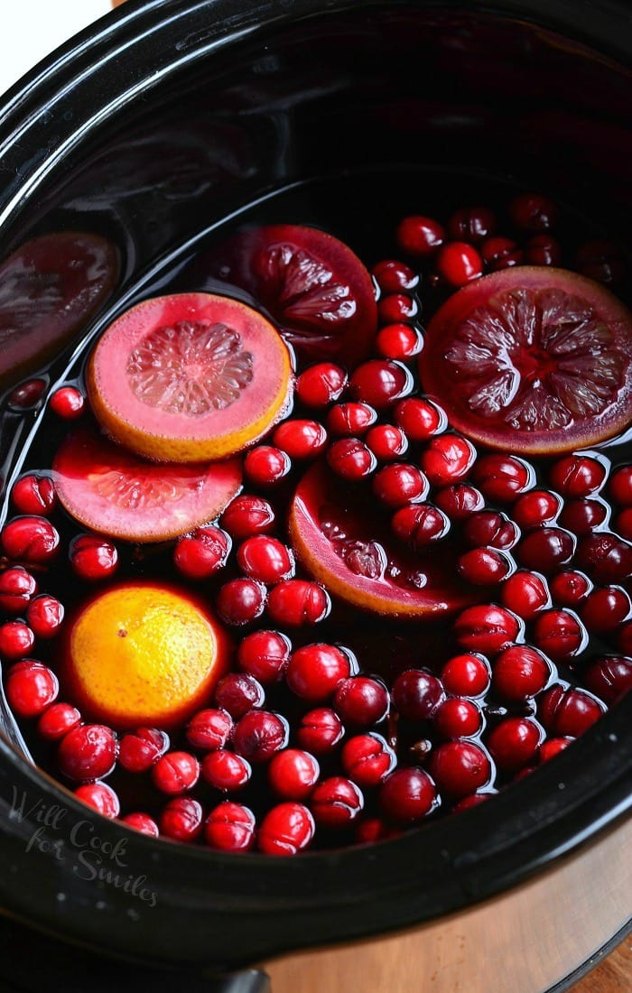 a crock pot shown cooking spiced orange cranberry sangria