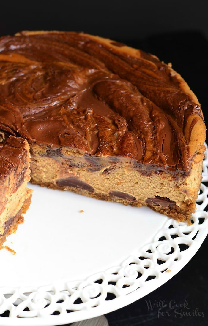 cheesecake with slice missing on a white cake stand