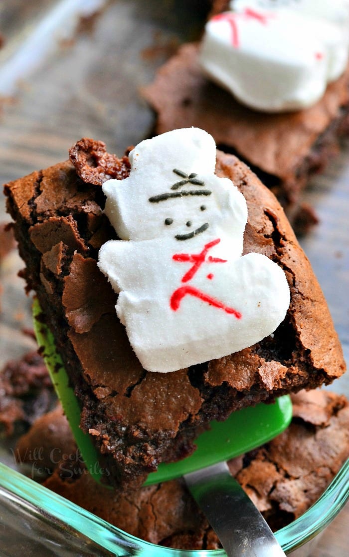 Brownies with snowman marshmallows on top on a green spatula
