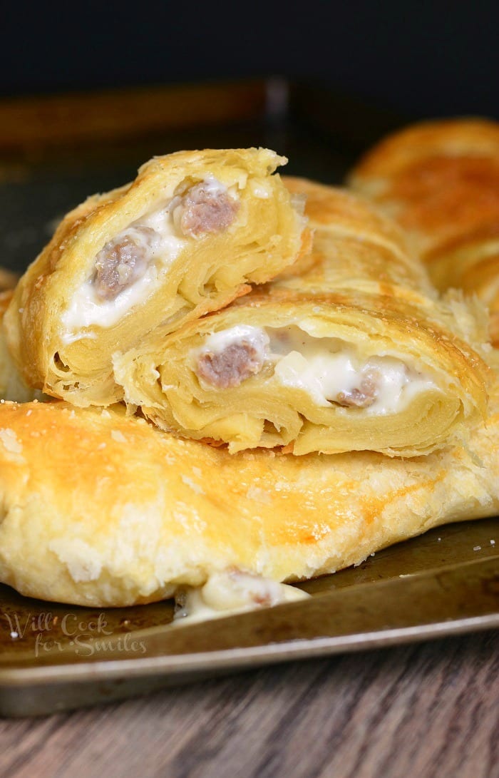 Sausage and gravy pastries piled on a baking try on a wooden table