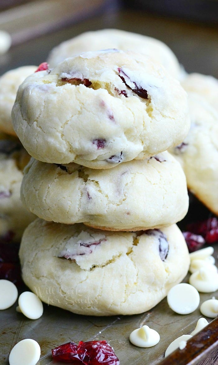 White Chocolate Cranberry Soft and Chewy Crinkle Cookies on a baking sheet with white chocolate chips and cranberries around it