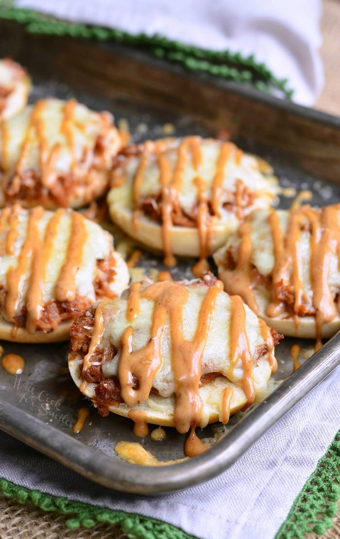 Metal baking sheet tray with asiago BBQ chicken bagel bites with sauce drizzled across the top
