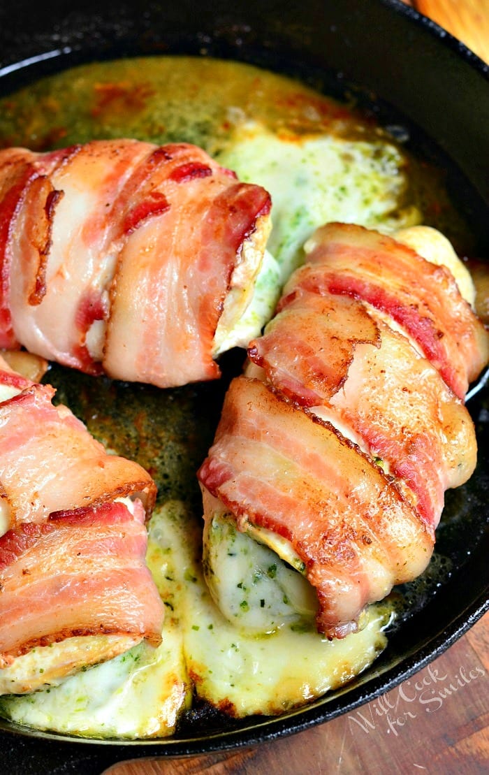 top view bacon wrapped chicken breast with cheese in a cast iron pan