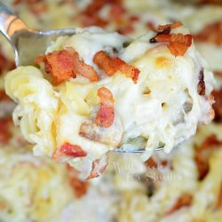 scooped chicken alfredo pasta casserole with a spoon .