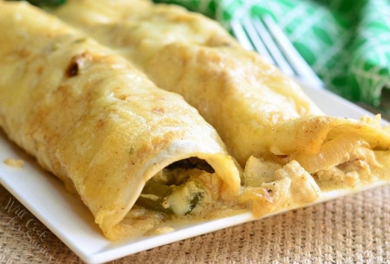 Roasted pablano and chicken enchiladas on a white rectangular plate with a green and white cloth in the background and a fork to the right viewed close up