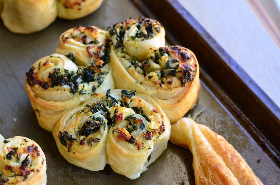 spinach and feta pastry shamrocks on a baking sheet pan as viewed close up