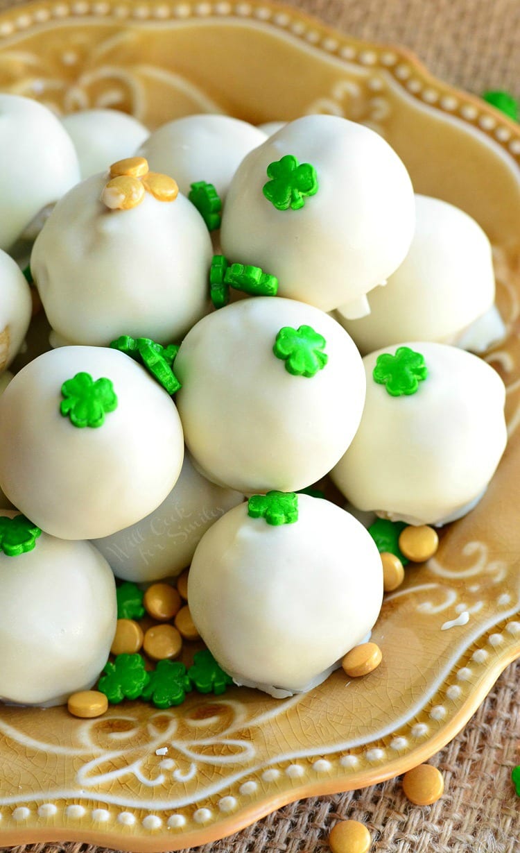 Baileys cookie dough truffles piled onto a decorative golden yellow plate with st patty's day candies sprinkles around them as shown from above