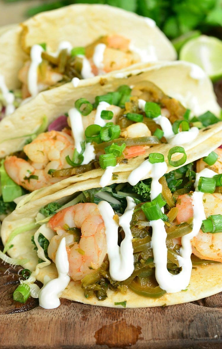 Top view of tequila Lime Shrimp Tacos with sour cream and green onions on top