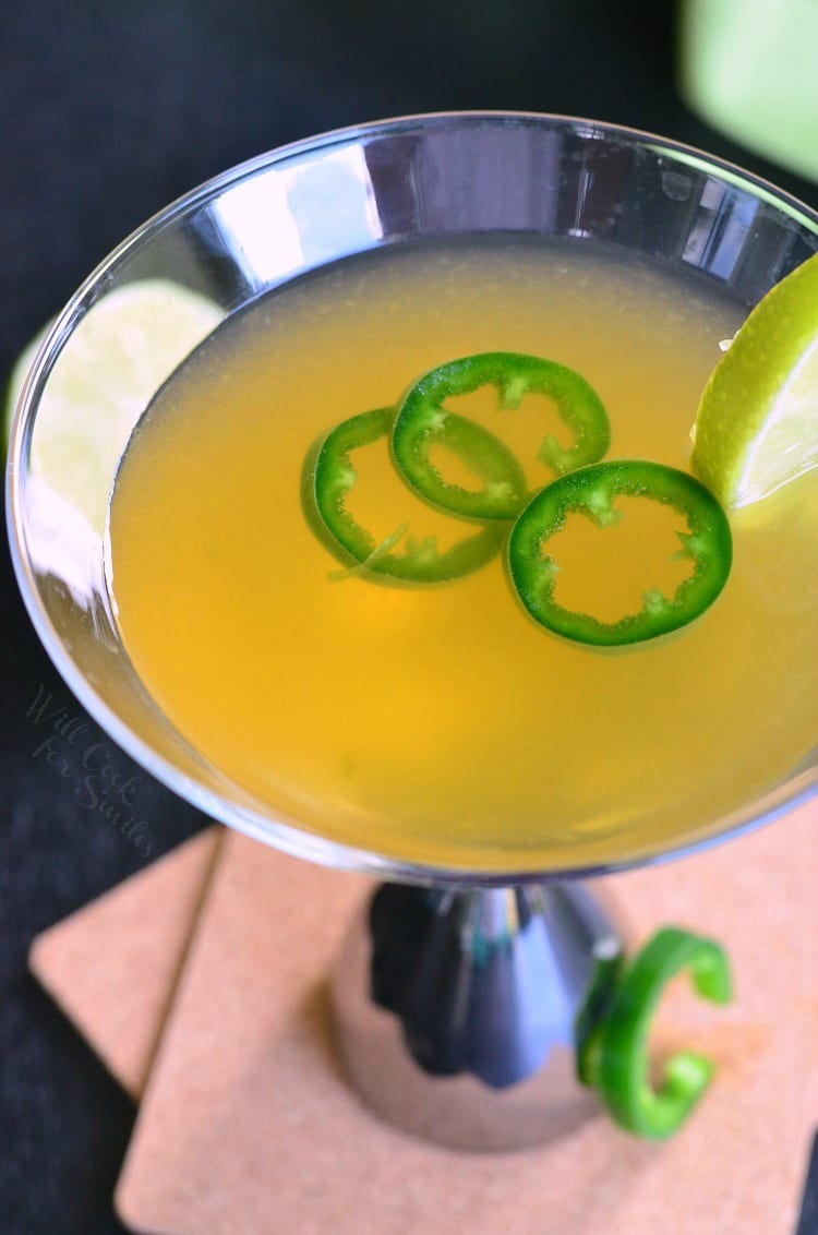 Decorative martini glass filled with Jalapeno Margatini garnished with a slice of lime and a slice of jalapeno leaning up against base of glass as viewed from above