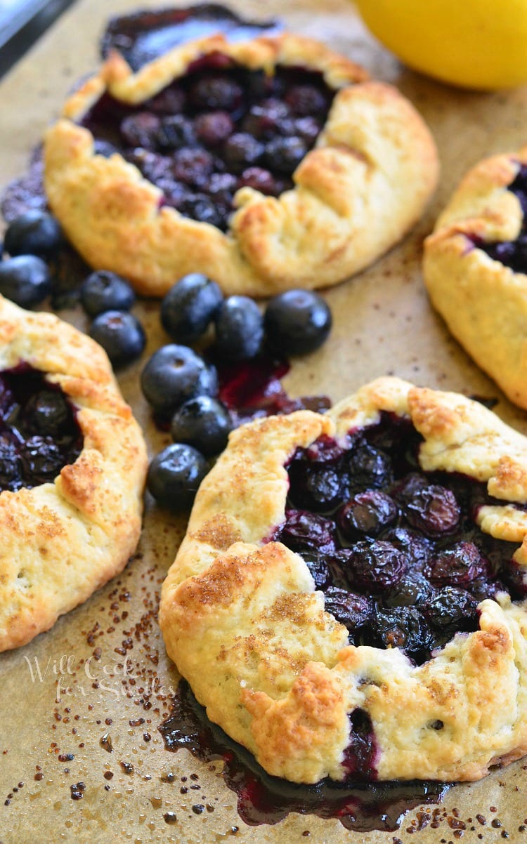 Blueberry Vanilla Lemon Galette on parchment paper with blueberries around it