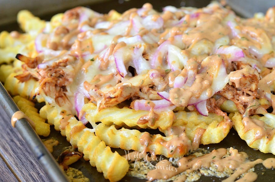 BBQ Ranch Chicken Loaded Fries with chicken, cheese, and red onions on a baking dish