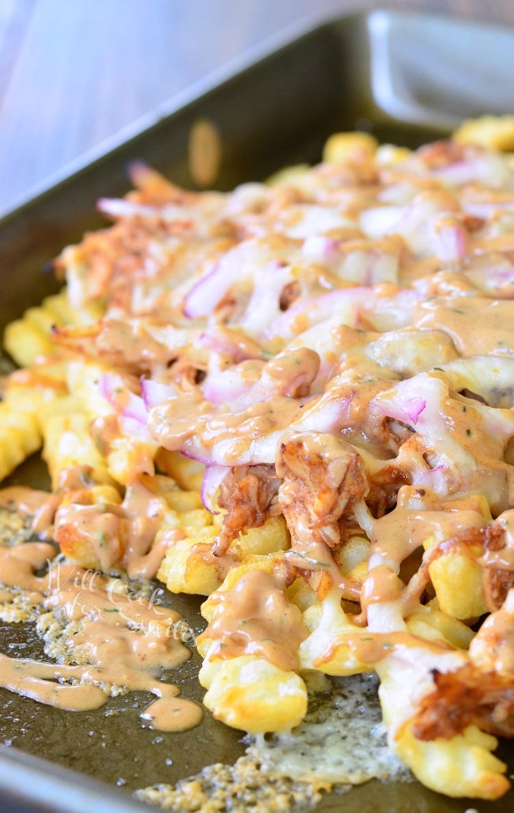 BBQ Ranch Chicken Loaded Fries with chicken, cheese, and red onions on a baking dish