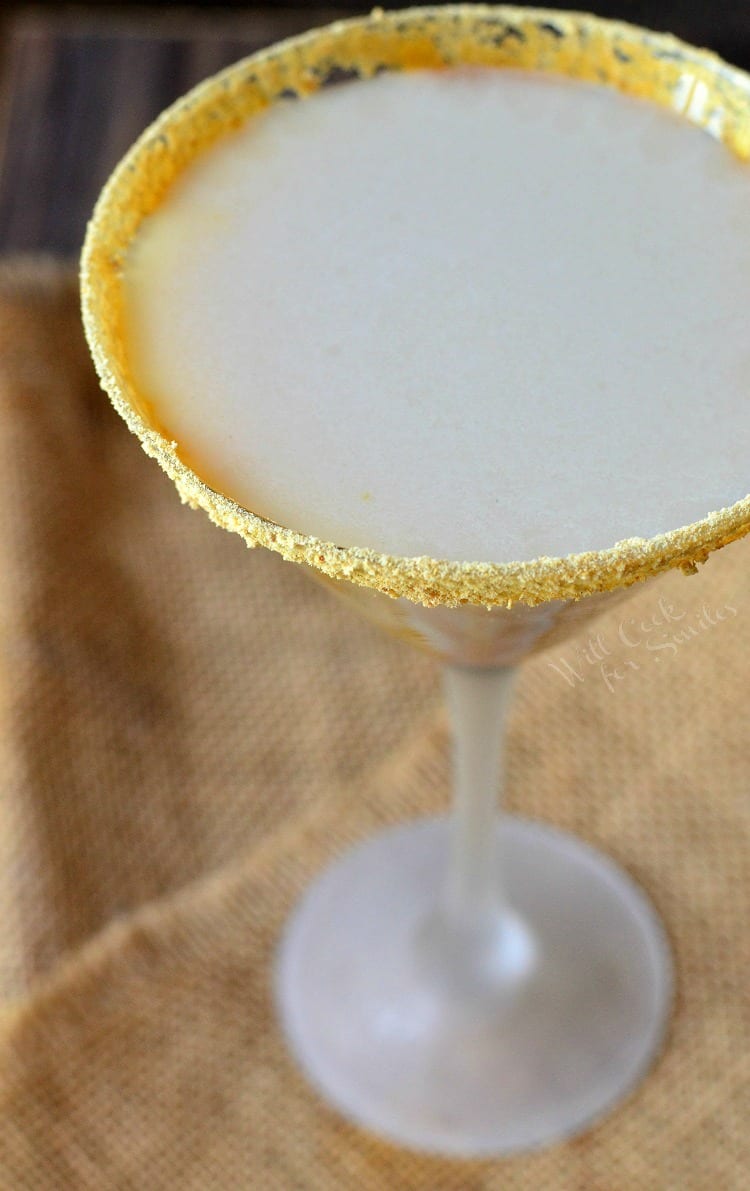 top view photo of Caramel Cake Martini in a martini glass with caramel topping around the glass sitting on a burlap table cloth