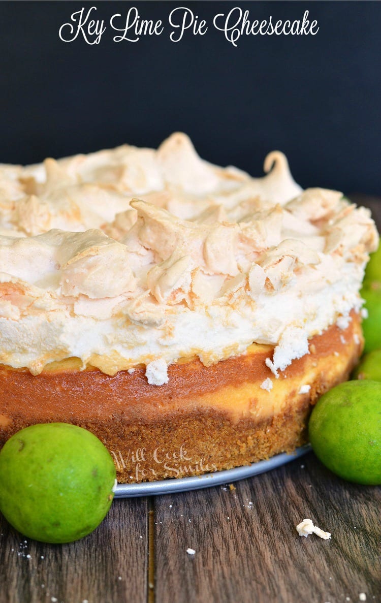 Key Lime Pie Cheesecake with meringue on top on a table with limes