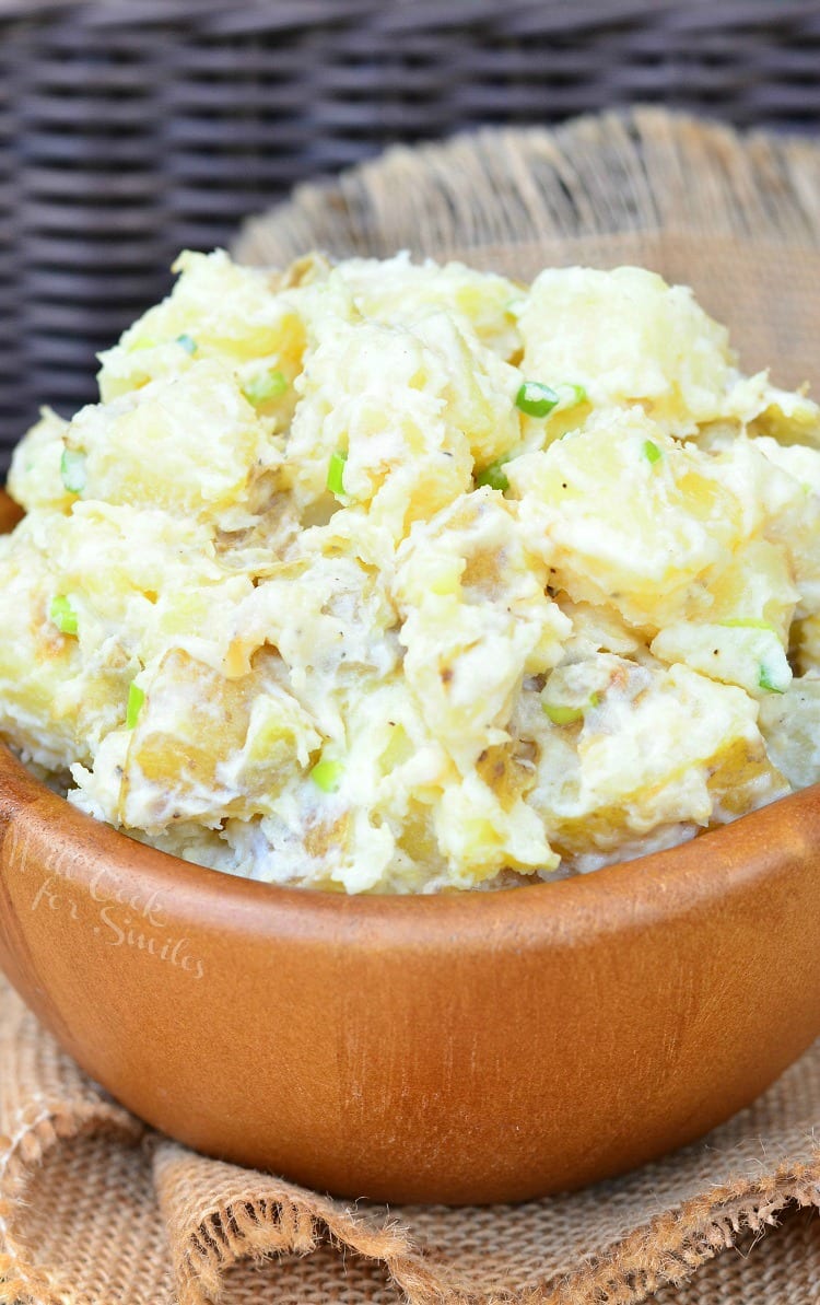 Wooden bowl filled with roasted garlic asiago potato salad on a tan cloth