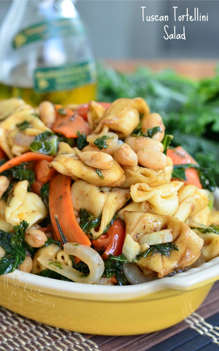 Tuscan Tortellini Salad with carrots, onions, and spinach in a yellow bowl