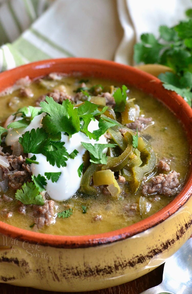 Ground beef with poblano peppers in a soup bowl with sour cream and cilantro on top