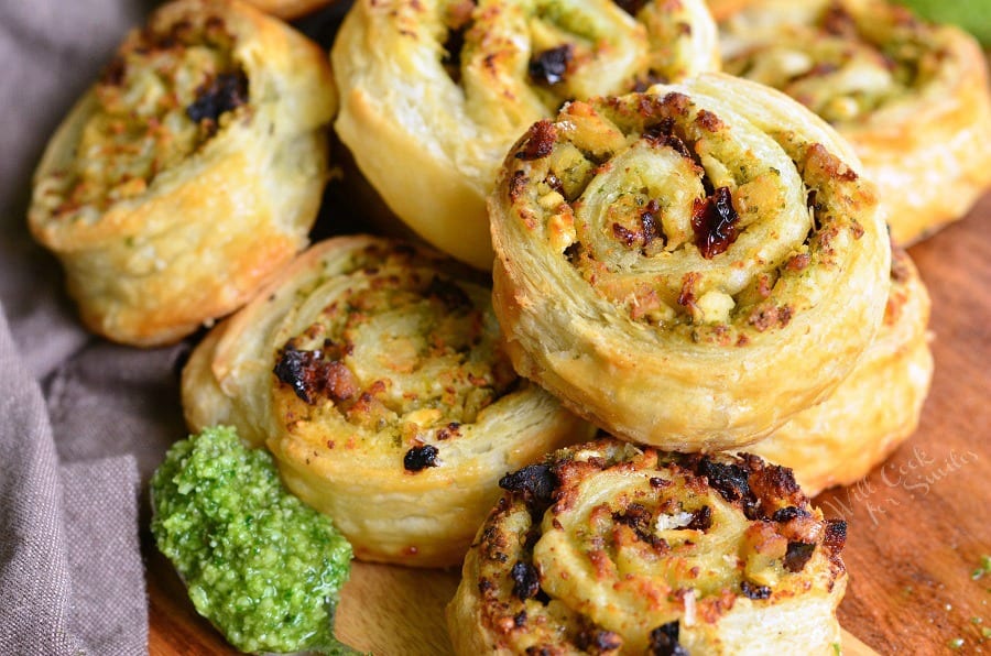 Pesto Chicken and Sun Dried Tomato Pinwheels on a cutting board with a spoon of pesto