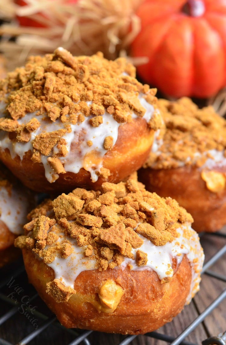Pumpkin Cheesecake Doughnuts with Gingersnap Crumb on top on a cooling rack