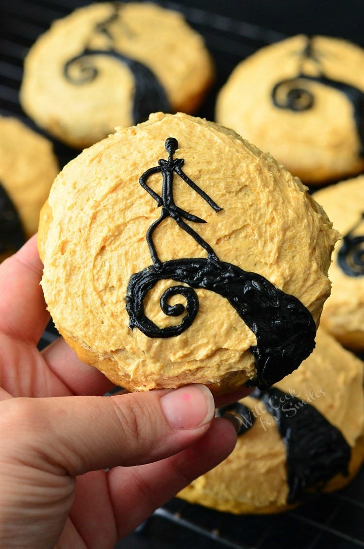 Holding a The Nightmare Before Christmas Cookies. Orange frosted cookies some with Jack made out of frosting