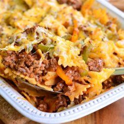 scooping some pasta and beef casserole from the baking dish with metal ladle.