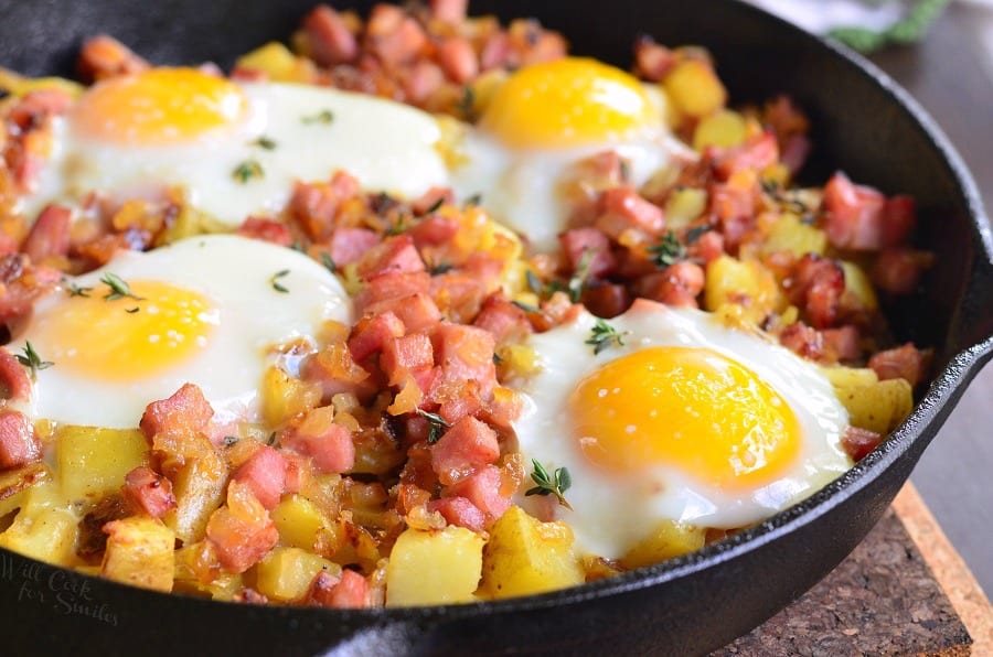 ham and potato mixture in a skillet topped with four eggs.