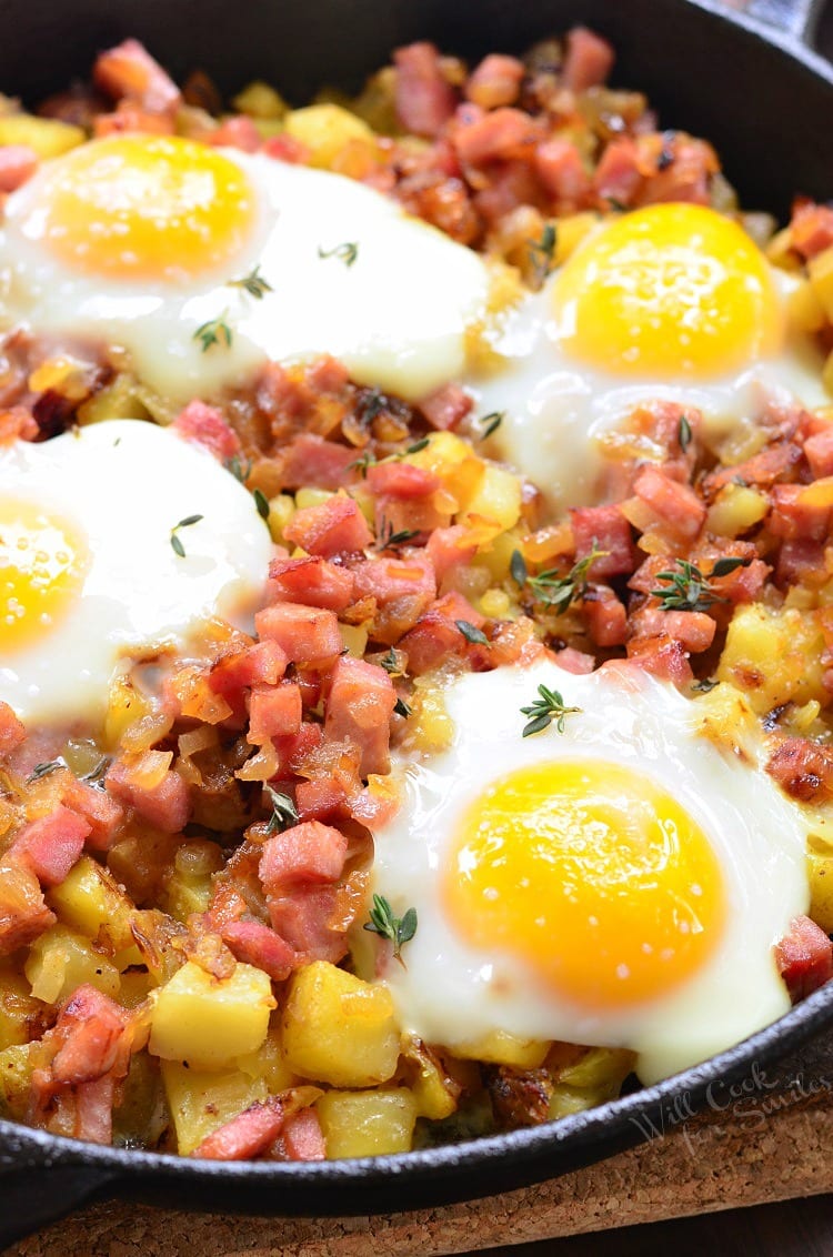 flavorful potato bake in a skillet with cubed potatoes, ham, and topped with sunny side up eggs.