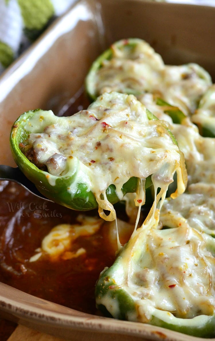 pulling out one stuffed green pepper with cheese from the pan. 
