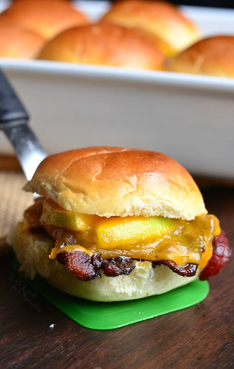 Apple Bacon Cheddar Baked Sliders on a green spatula on a wood cutting table