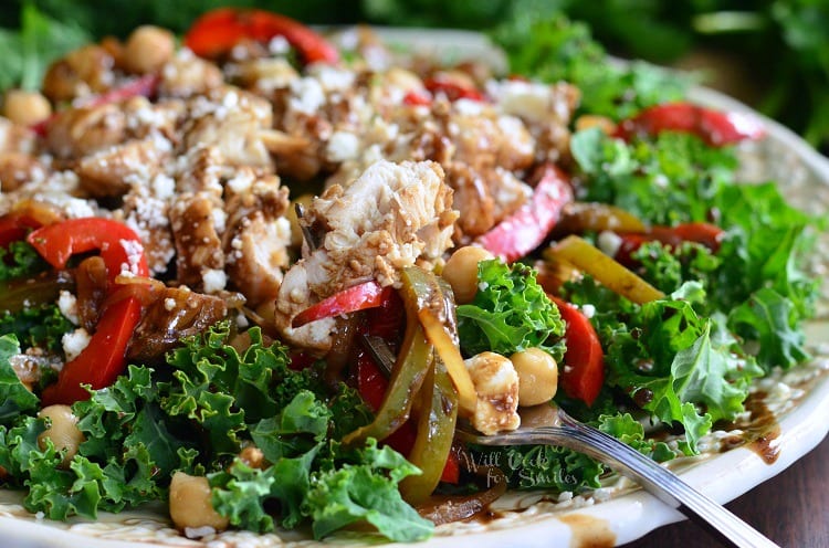 White decorative bowl filled with balsamic chicken, veggies and chick pea salad as viewed close up.