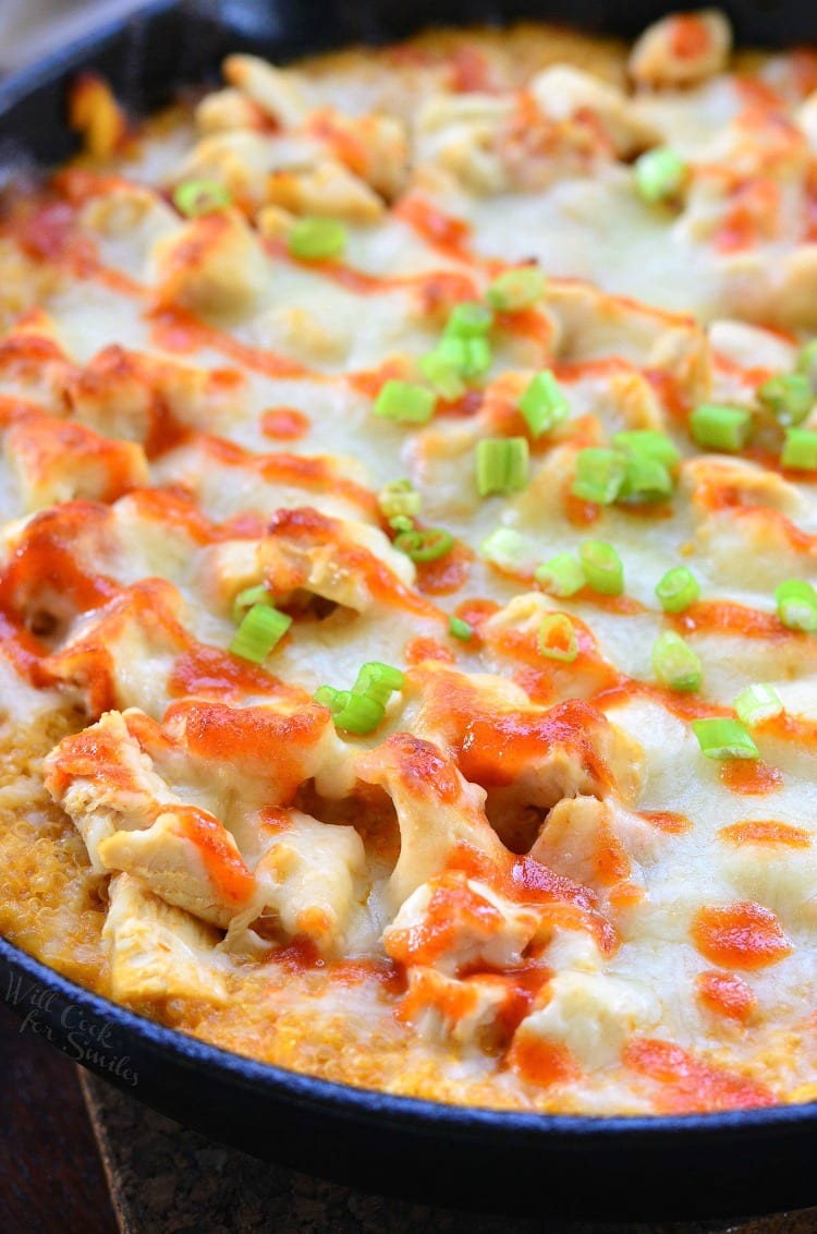 close up of Creamy Sriracha Chicken and Quinoa Bake in a cast iron skillet with a spoon lifting some out