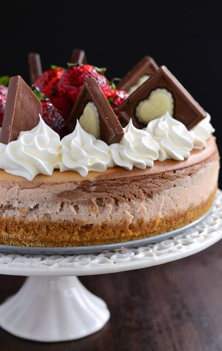 Chocolate Strawberry Marbled Cheesecake on a cake stand on a wood table