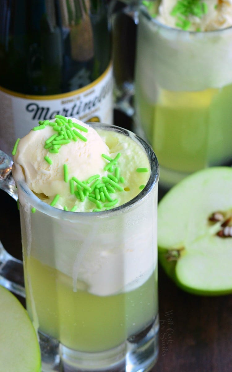 Green Apple Ice Cream Soda Float in a glass mug with Martinelli's Sparkling Apple Cider in the background a sliced apples on a table