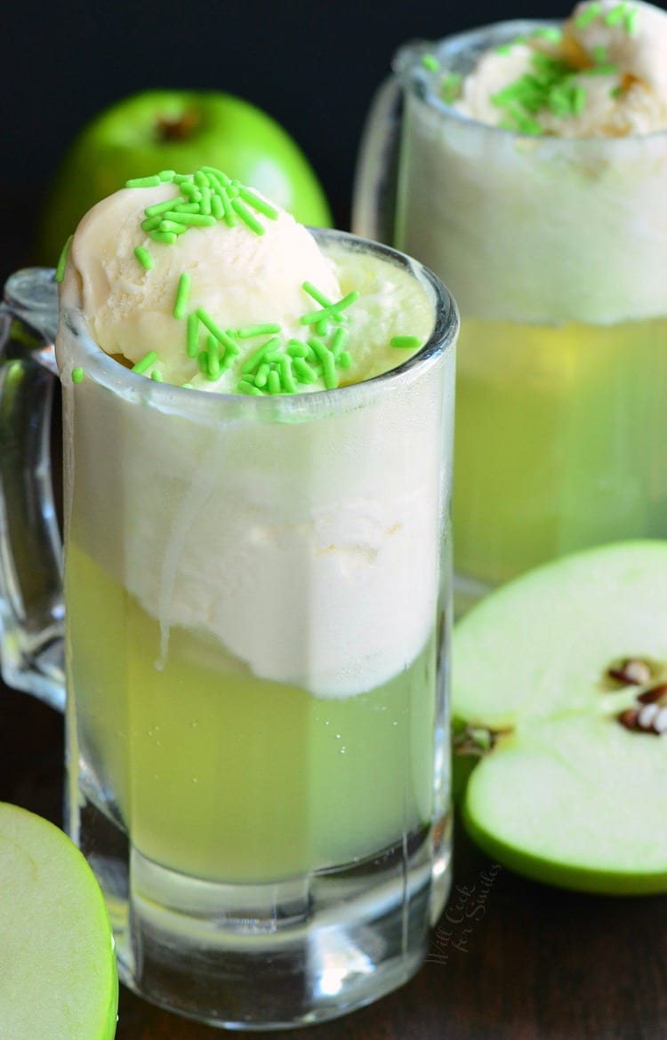 Green Apple Ice Cream Soda Float in a glass mug with green sprinkles on top with apples around the tables
