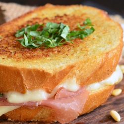 whole Italian grilled cheese with prosciutto on a cutting board.