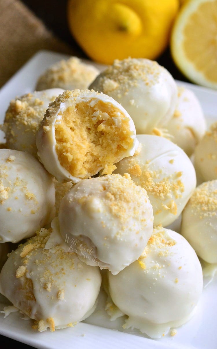 Lemon Oreo Coconut Cookie Truffles on a white plate with a bite taken out of one and lemons in the background