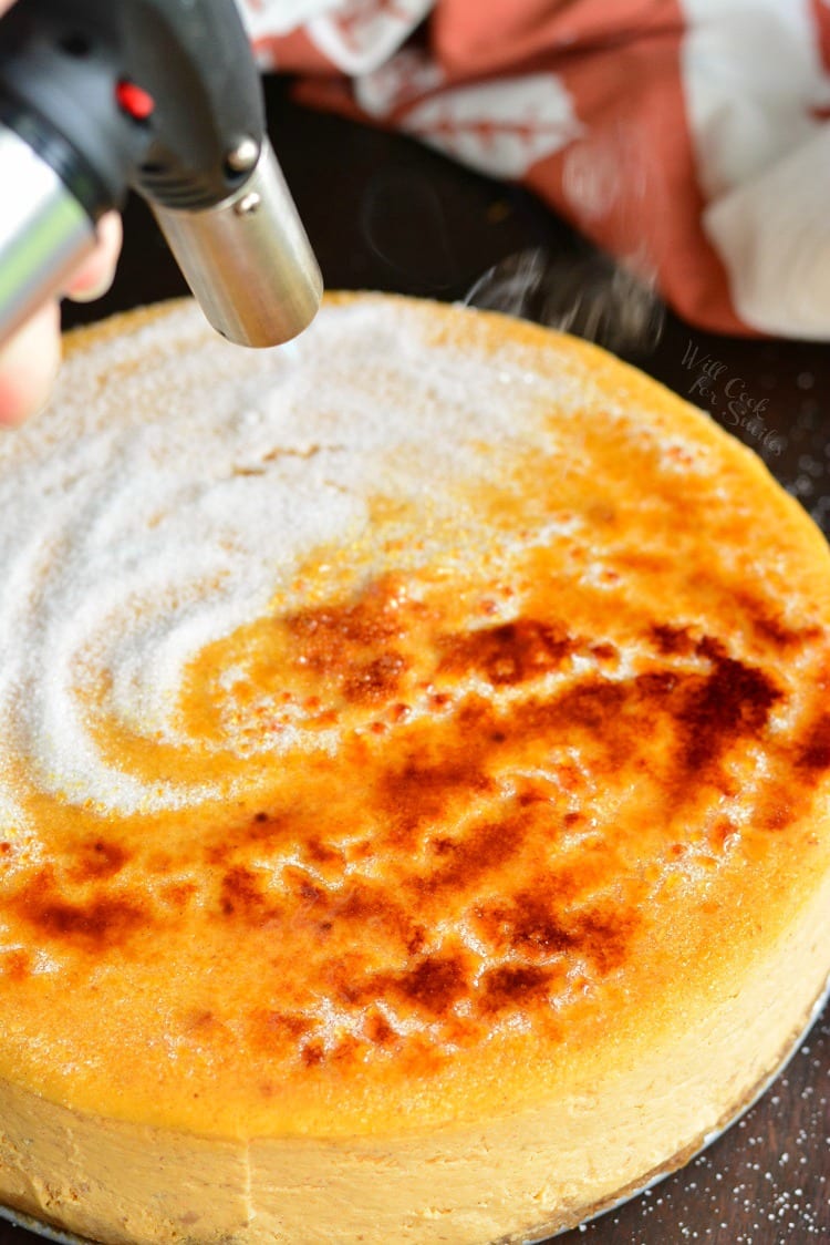 using a culinary torch to caramelize sugar on a cheesecake.