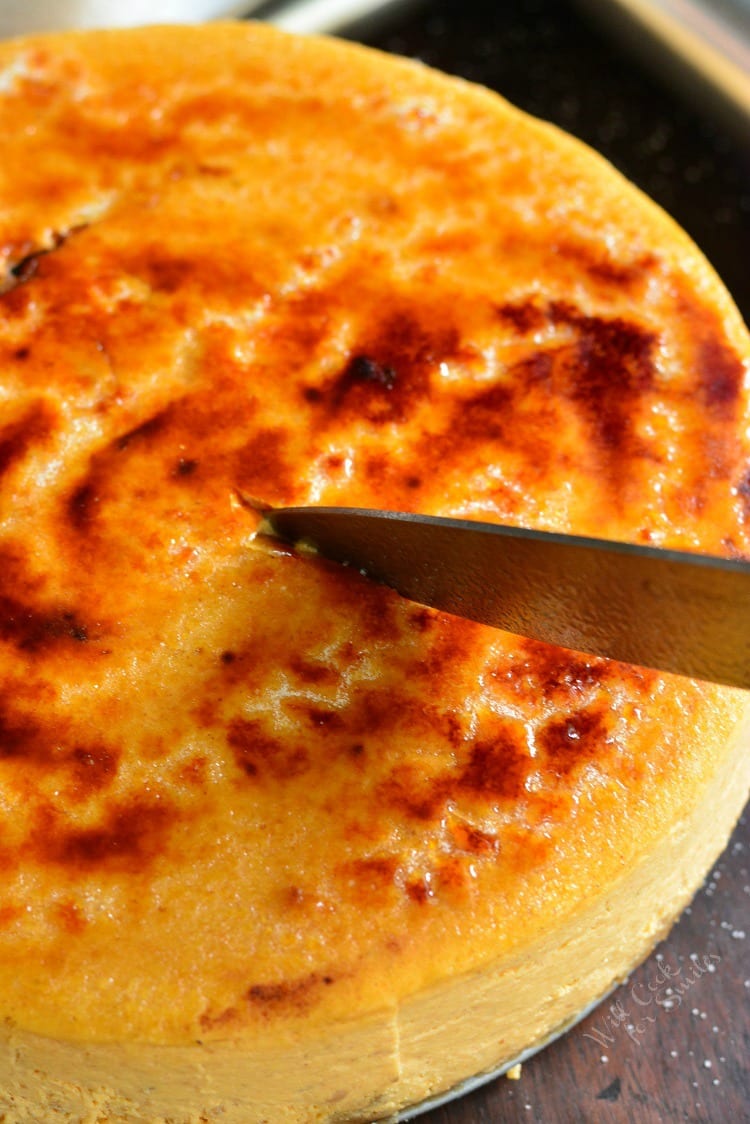 using a knife to cut a slice from the pumpkin cheesecake.