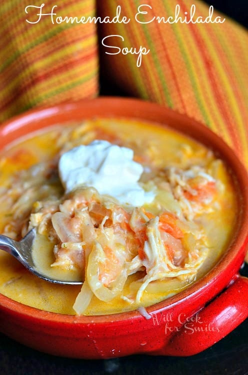 Chicken Enchilada Soup in a bowl with sour cream and a spoon
