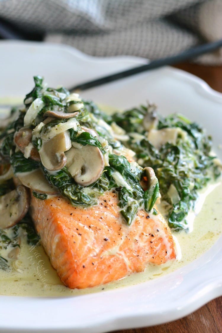 salmon forestine with spinach and mushrooms on top on a white plate.