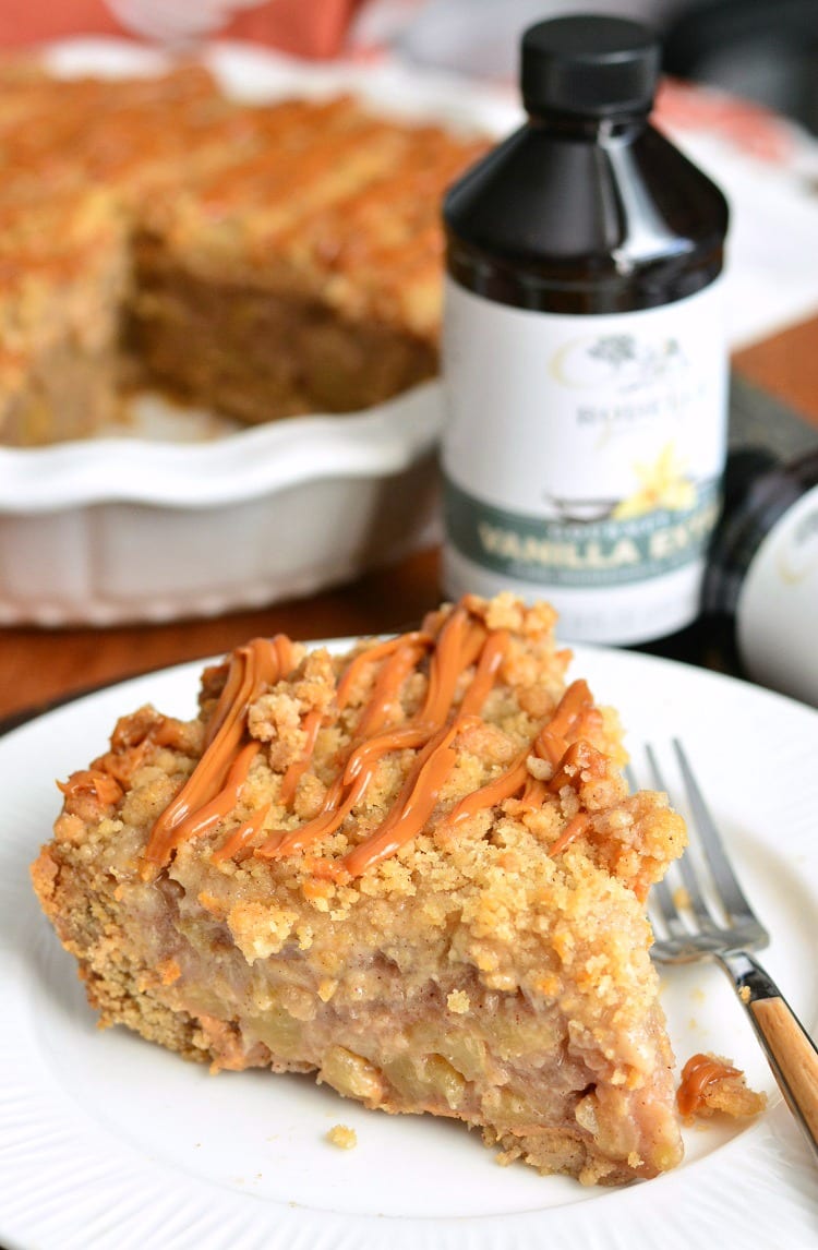Caramel Apple Cookie Crust Pie on a plate with a fork with the rest of the pie in the pie pan and a bottle of vanilla in the background