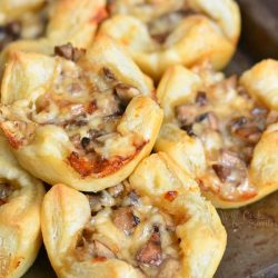 stacked buttery and fluffy mushroom cheese puffs on a baking sheet.