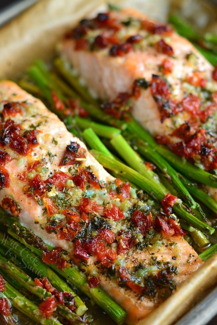 Sun Dried Tomato Lemon Baked Salmon and Asparagus in parchment paper on a baking sheet