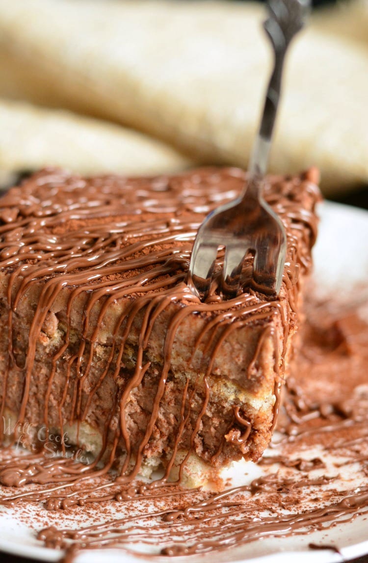 a fork piercing a no egg Nutella tiramisu on a plate drizzled with Nutella.