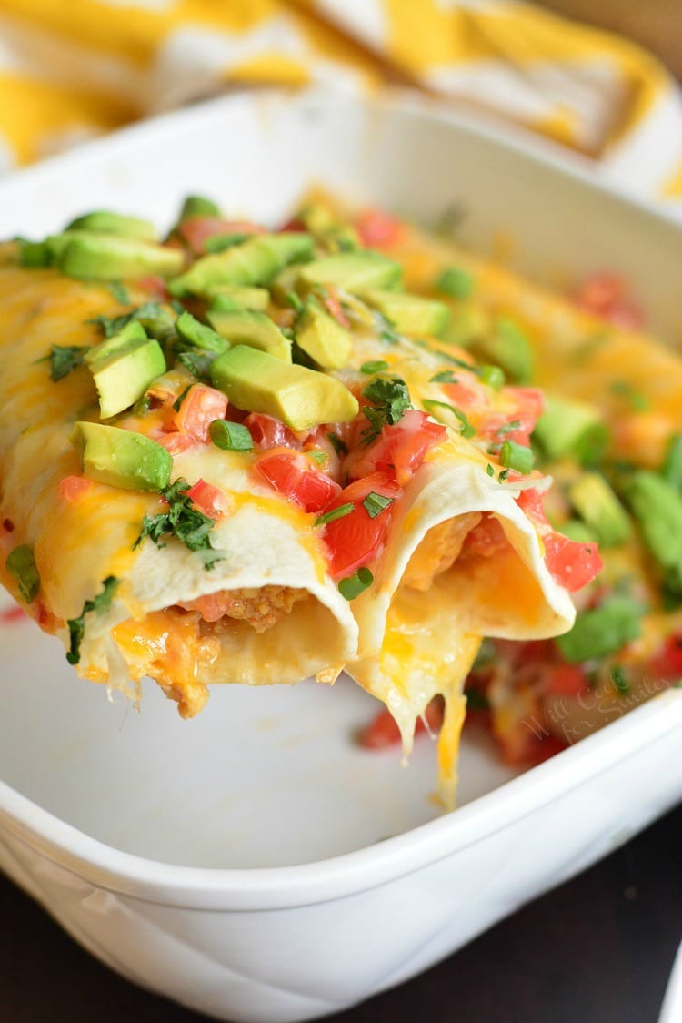Western Omelet Breakfast Enchiladas in a casserole dish being lifted out with a spatula