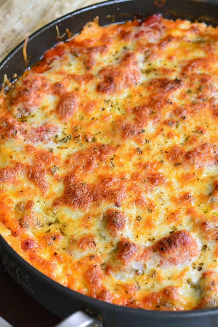 baked meatball dip in a large pan with cheesy layer on top.