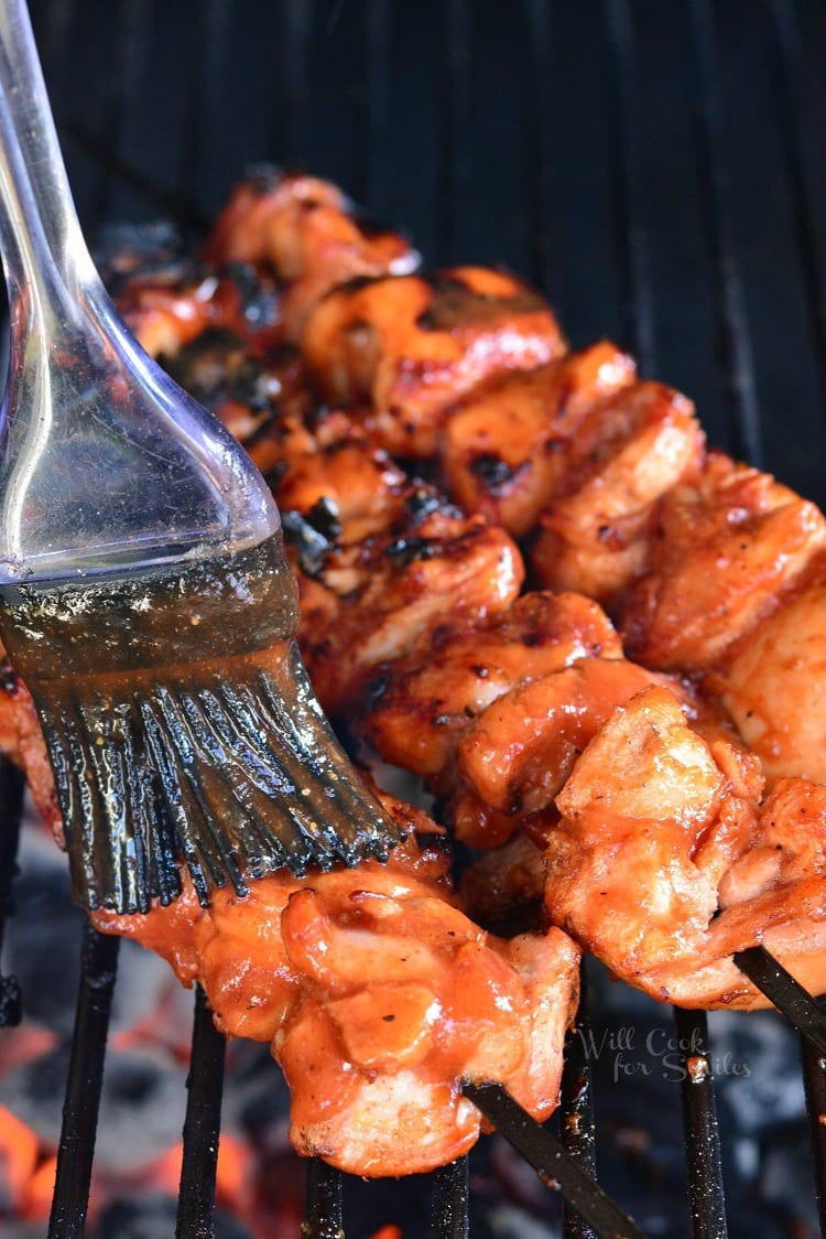 brushing Spicy BBQ sauce onto the Chicken Skewers on the grill