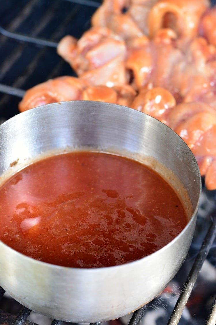 bbq sauce in a pot on the grill for chicken skewers