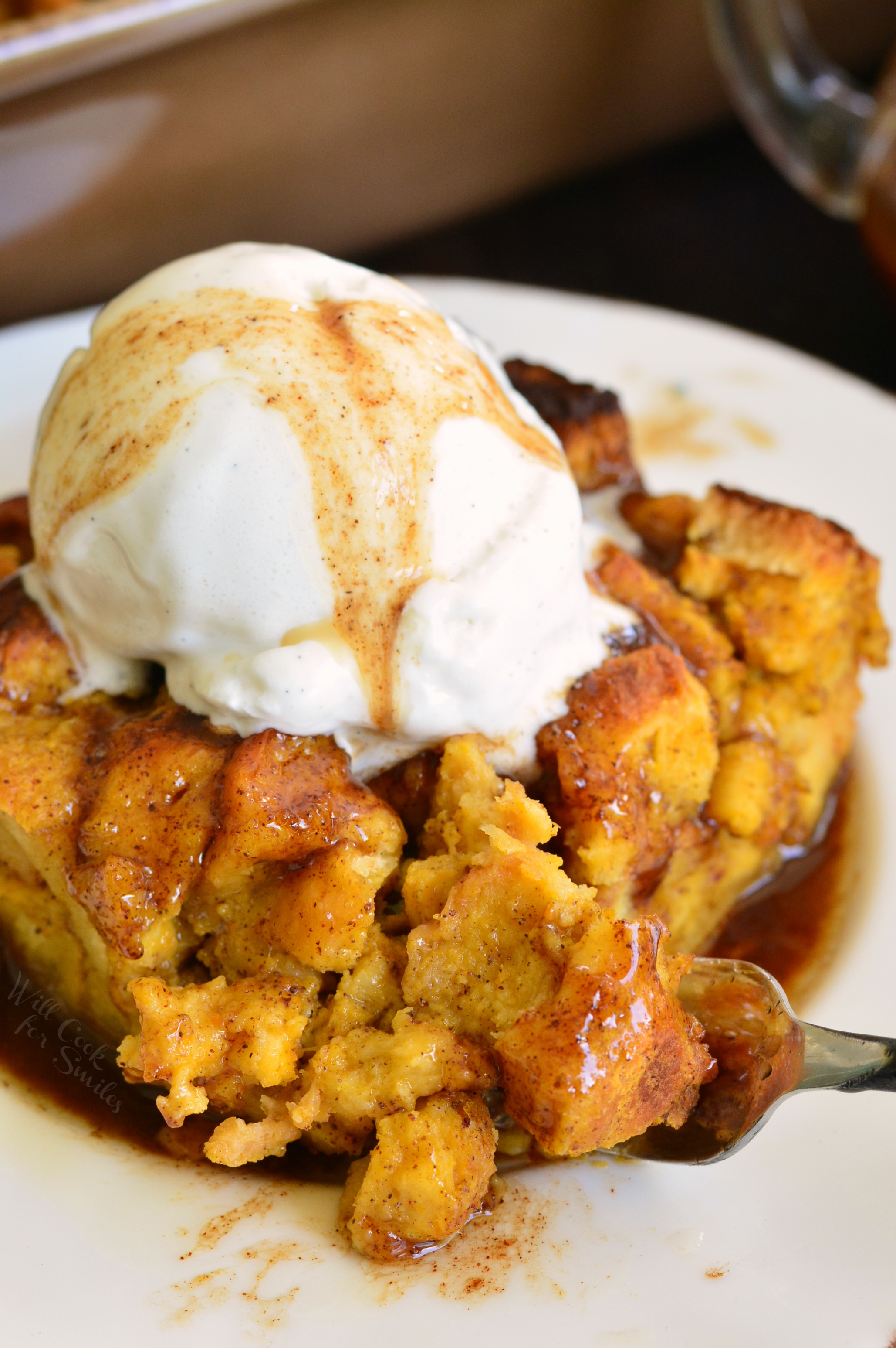 Brioche Pumpkin Bread Pudding on a plate with ice cream and a fork with some on it
