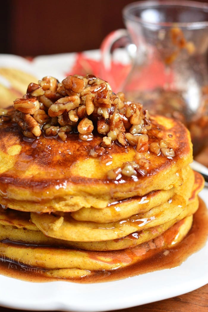 a stack of several pumpkin pancakes topped with cinnamon pecan syrup.